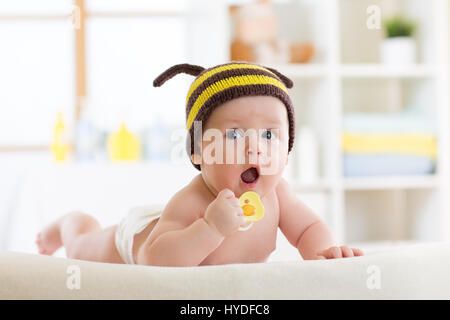 Carino bambino con succhietto sul letto di casa Foto Stock