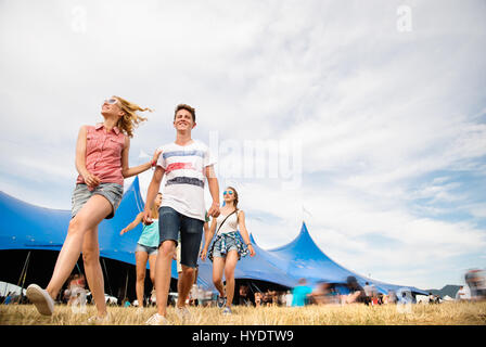 Gli adolescenti al festival musicale estivo nella parte anteriore del big blue tenda Foto Stock