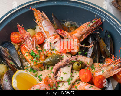 Variopinto pesce fresco con spezie e verdure sulla piastra blu nel ristorante. Close up Foto Stock