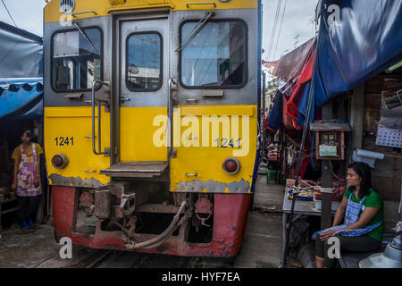 MAE KLONG - TAHILAND - CIRCA NEL SETTEMBRE 2014: Treno in avvicinamento le bancarelle all'Maeklong mercato ferroviario Foto Stock