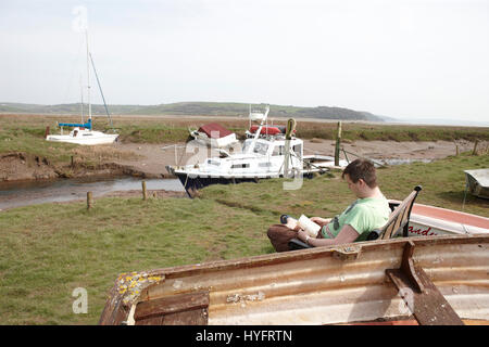 Uomo di lettura da parte dell'Oceano su un banco, il Festival letterario, Laugharne, Wales, Regno Unito Foto Stock