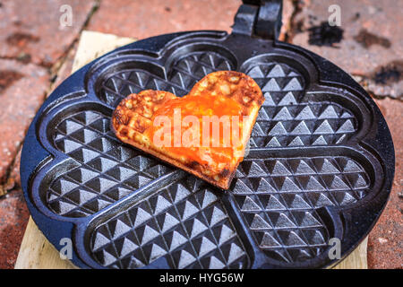Singola cialda cuore con orange jam topping, giacente in waffle ferro da stiro Foto Stock