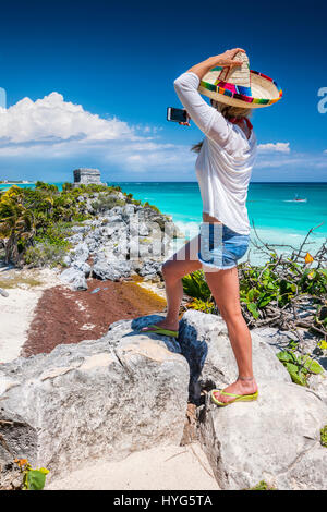 Una donna con il cappello di paglia di prendere foto di rovine Maya di Tulum, Messico Foto Stock