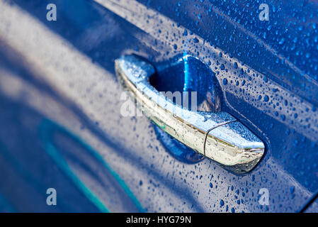 Chrome wet auto gestire close-up. Gocce di pioggia su auto blu porta Foto Stock