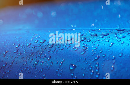 Gocce d'acqua sulla vettura di metallo vernice blu. Primo piano delle gocce di pioggia sulla superficie blu Foto Stock