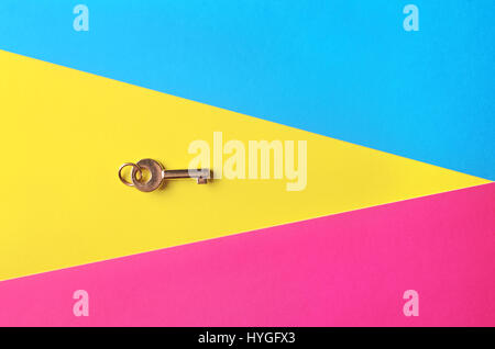 Golden Key su un sfondo multicolore, vista dall'alto. Alla moda foto colorate. Stile minimal con carta colorata sullo sfondo. Lay piatto fashion concept: golden Foto Stock