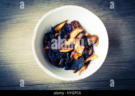 Frutta secca in bianco ciotola sul pavimento in legno o tavolo, prugna, Apple Foto Stock