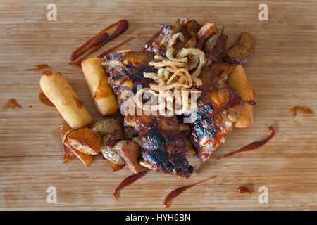 American grigliate di nervature sulla griglia condito con salsa barbecue con anelli di cipolla e calda di patate croccanti con purea di patate-riempito crocchette - American Foto Stock