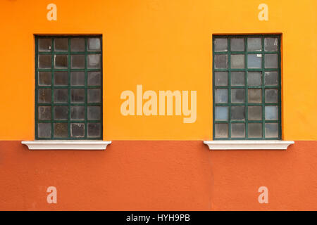 Windows su un rosso e giallo parete nell'isola di Burano, Venezia, Italia. Foto Stock