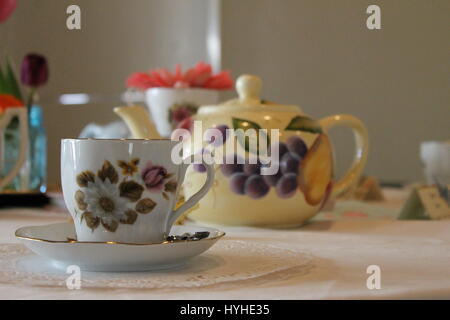 Una focalizzazione di tazza da tè su una tabella con una offuscata tè pentola in background Foto Stock