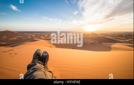 Un uomo è godersi il tramonto sulle dune del deserto del Sahara - Merzouga - Marocco Foto Stock