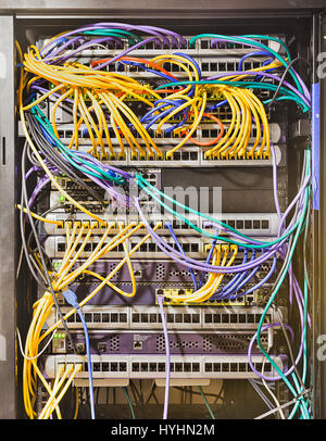 Aprire il cabinet del rack nel moderno centro dati con pannelli montati, switch, router, server e altre apparecchiature telecomm collegati da cavi patch. Foto Stock