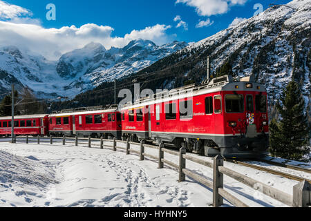 Vista invernale del Bernina Express il trenino rosso con il Bernina e Morteratsch ghiacciaio in background, Grigioni, Svizzera Foto Stock