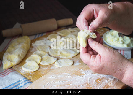 Vecchia donna con le mani in mano la cottura tradizionale ucraino gnocchi di patate con formaggio Foto Stock