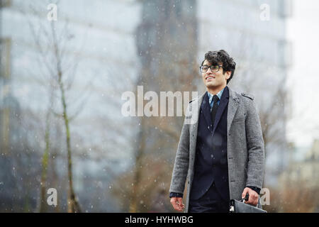 Giovane Imprenditore sorridente in nevicata Foto Stock
