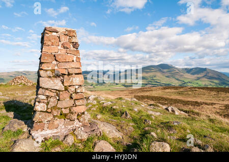 Trigpoint sul vertice di Binsey nel Lake District inglese con una vista della gamma Skiddaw nella distanza. Foto Stock