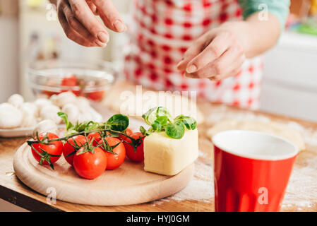 Donna preparare la pizza in cucina Foto Stock