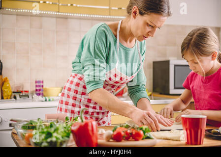 Madre e figlia preparare la pizza in cucina Foto Stock