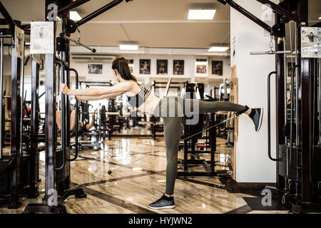 Giovane donna fitness eseguire esercizio con esercizio-macchina Crossover cavo in palestra, la foto in orizzontale Foto Stock