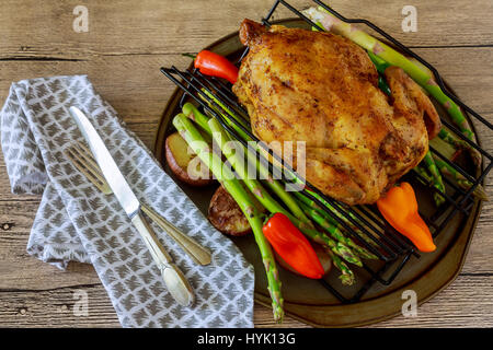 Dorate e croccanti della pelle di pollo grigliato in forno con spicchi di patate e porri in ghisa pan su vecchie tavole di legno, tagliere con fette di cipolla e Foto Stock