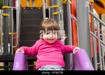 Bambino sulla parte superiore della diapositiva nel parco giochi Foto Stock