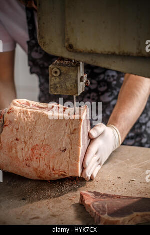 Lavoratore tagli su pezzi uguali carni bovine congelate Carni in work shop in fabbrica. Foto Stock