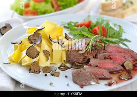 Frittura di filetto di manzo con pasta italiana e fette di dolce autunno nero tartufi, servita con un misto di insalata di contorno e baguette Foto Stock