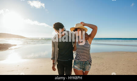 Inquadratura orizzontale di felice coppia giovane sulla spiaggia. Giovane uomo e donna che cammina sulla riva del mare e ridere. Foto Stock
