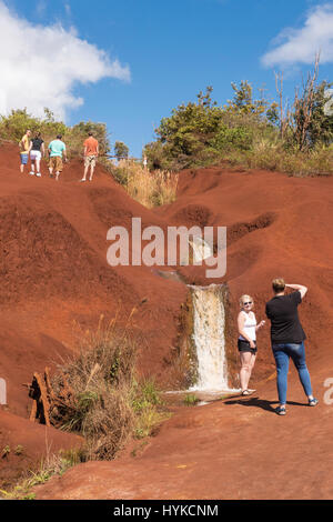 I turisti in corrispondenza di un bordo strada cascata in Red Rocks, Koke"e del parco statale, il Canyon di Waimea, Kauai, Hawaii, STATI UNITI D'AMERICA Foto Stock