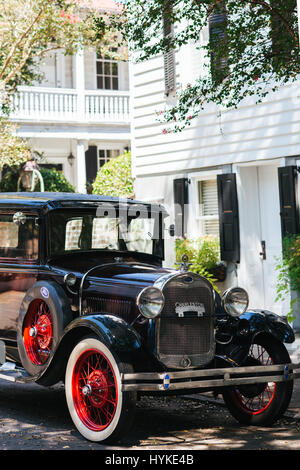 Un nero Ford 1928 un modello con ruote rosse parcheggiato di fronte a una casa in bianco e nero di otturatore casa coloniale nel centro storico di Charleston, Carolina del Sud. Foto Stock