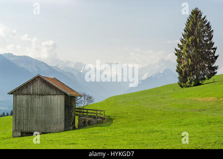 Vista dal fienile in legno a montagne coperte di neve in primavera Foto Stock