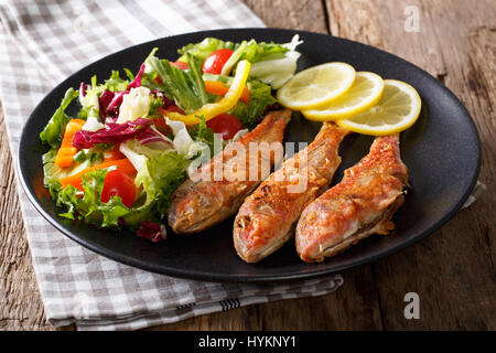 Pesce fritto delizioso triglie con insalata fresca closeup su una piastra orizzontale. Foto Stock