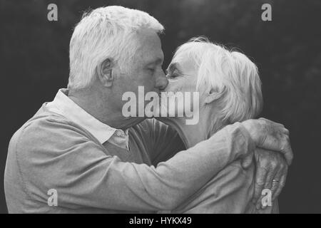 Carino coppia senior baciare calorosamente all'aperto Foto Stock