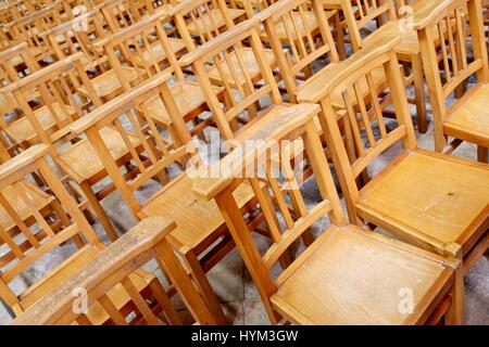 Un enorme gruppo di sedie di legno disposte in righe. Foto Stock