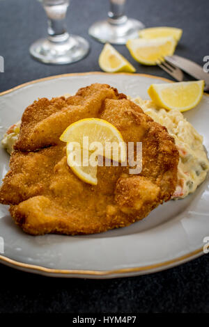 La carne di maiale fritto schnitzel con tradizionale insalata di patate su nero tavolo di pietra Foto Stock