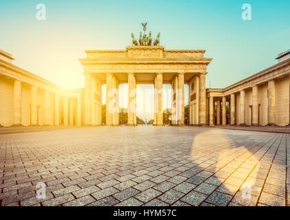 Famoso Brandenburger Tor (Porta di Brandeburgo), uno dei più noti monumenti e simboli nazionali della Germania, in beautiful Golden. La luce del mattino presso Sun Foto Stock