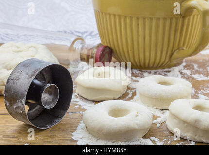 Close up foto di ciambelle fresche arrotolato su legno infarinata tavolo da cucina e ciambella rotonda taglierina Foto Stock