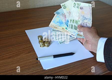 Braccio della persona d'affari nella camicia di contenimento valute di carta, euro, dollari e Lire con penna e moneta sulla carta nota Foto Stock