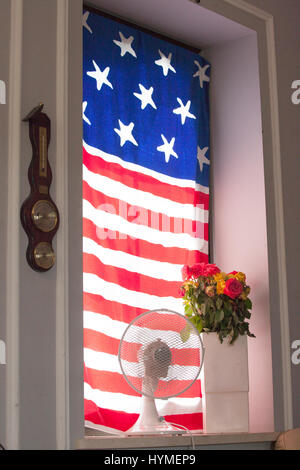 Patriottica bandiera americana-come decorazione per finestre con un vaso di fiori di avvizzimento e un ventilatore. Zawady Polonia centrale Europa Foto Stock