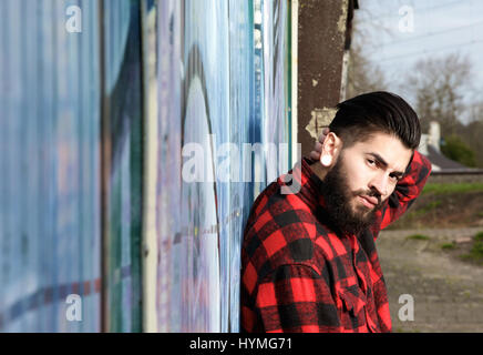 Close up ritratto di un uomo latino con la barba e piercing seduti all'aperto Foto Stock