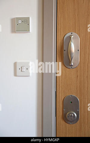Chiusura di una porta in un'unità psichiatrica sicura e residenziale. Mostra la maniglia della porta e il montaggio della serratura antilegatura, progettati per evitare il rischio di strangolamento Foto Stock