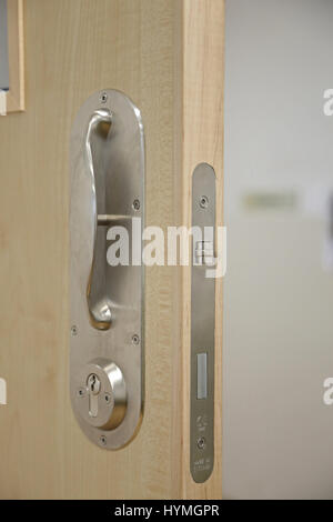 Chiusura di una porta in un'unità psichiatrica sicura e residenziale. Mostra la maniglia della porta e il montaggio della serratura antilegatura, progettati per evitare il rischio di strangolamento Foto Stock