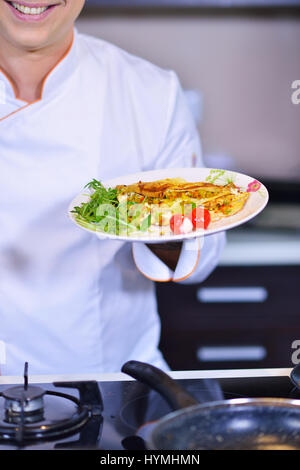 Mano d'uomo in possesso di un uovo. Bianco d'uovo di gallina. Lo Chef inizia a preparare frittata. Foto Stock