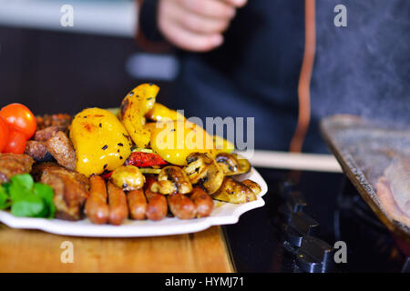 Salsicce alla griglia con verdure grigliate sul tavolo da cucina Foto Stock