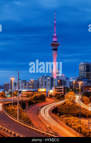 Auckland al crepuscolo, con percorsi auto illuminata su autostrada. Foto Stock