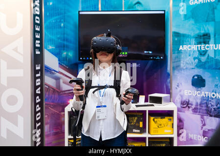 Ragazza la riproduzione di video gioco di realtà virtuale auricolare e controller palmare sviluppato da HTC Vive in mostra al Cebit 2017 di Hannover Messe, Germania Foto Stock