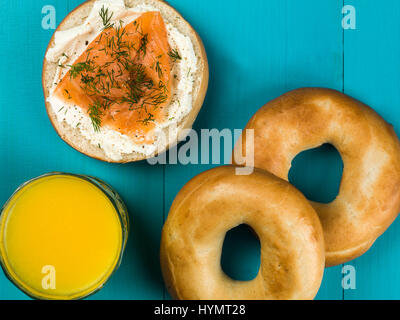 Salmone affumicato e crema di formaggio bagel contro uno sfondo blu Foto Stock