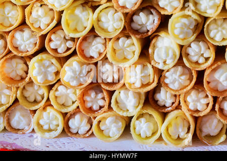 Righe di pane appena sfornato, ciambelle dolci o panini dolci con il riempimento e la polvere di zucchero bianco contro lo sfondo della carta, gustosi panini come alimento ideale per lun Foto Stock