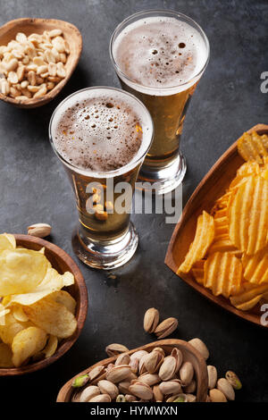 Lager boccale di birra e spuntini sul tavolo di pietra. Dadi, chips Foto Stock