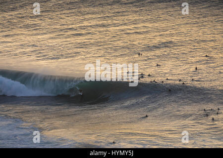 Un elevato angolo di visione di un surfista cattura un'onda durante un grande rigonfiamento a Pipeline sulla North Shore di Oahu. Foto Stock